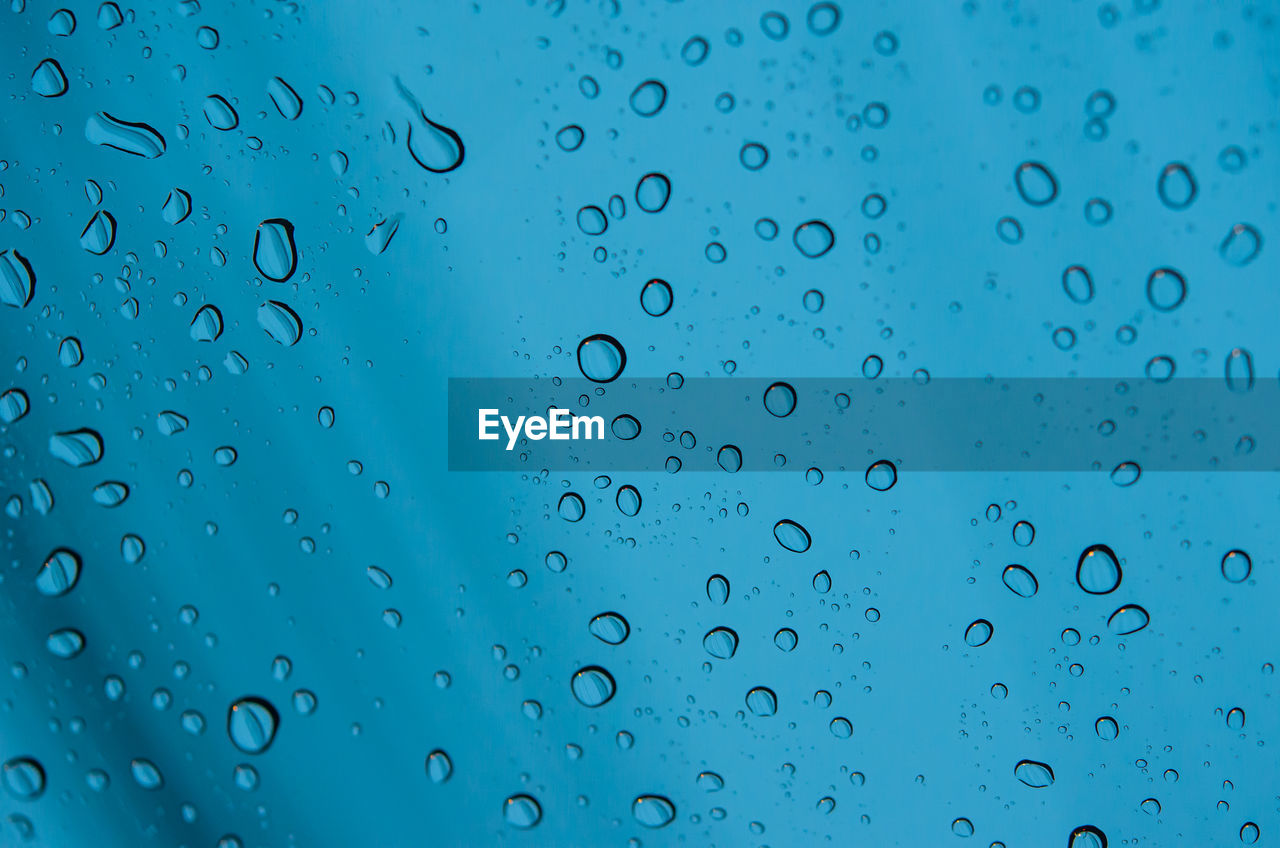 FULL FRAME SHOT OF RAINDROPS ON GLASS