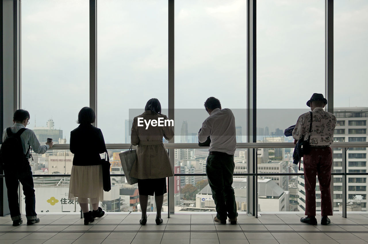 Rear view of people standing by railing against clear sky