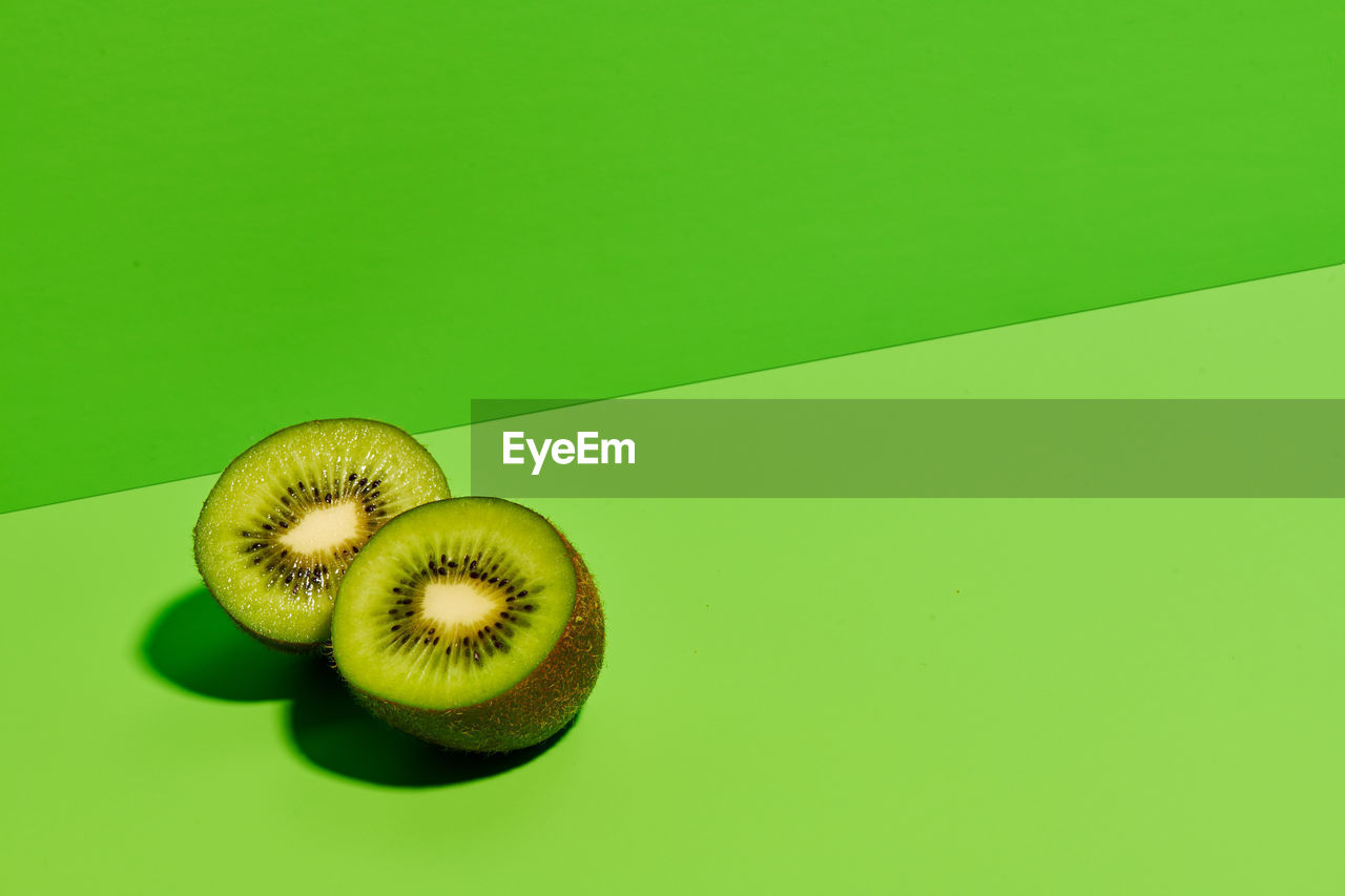 Half of delicious ripe kiwi fruit placed on green background in modern studio