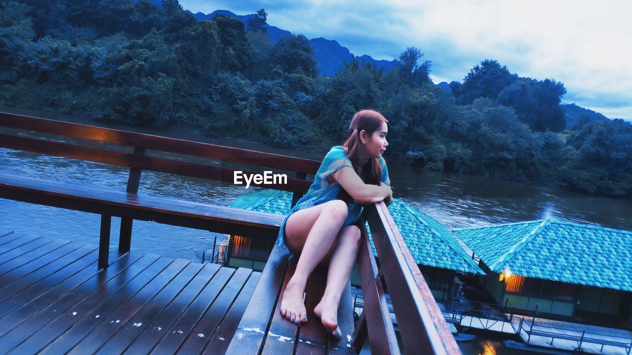 Full length of woman sitting on bench against sky