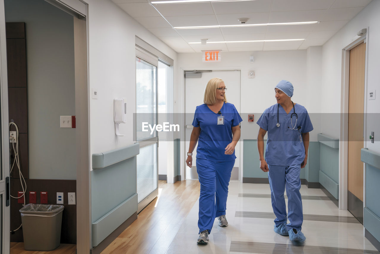 Surgeon and nurse talking while walking in hospital corridor