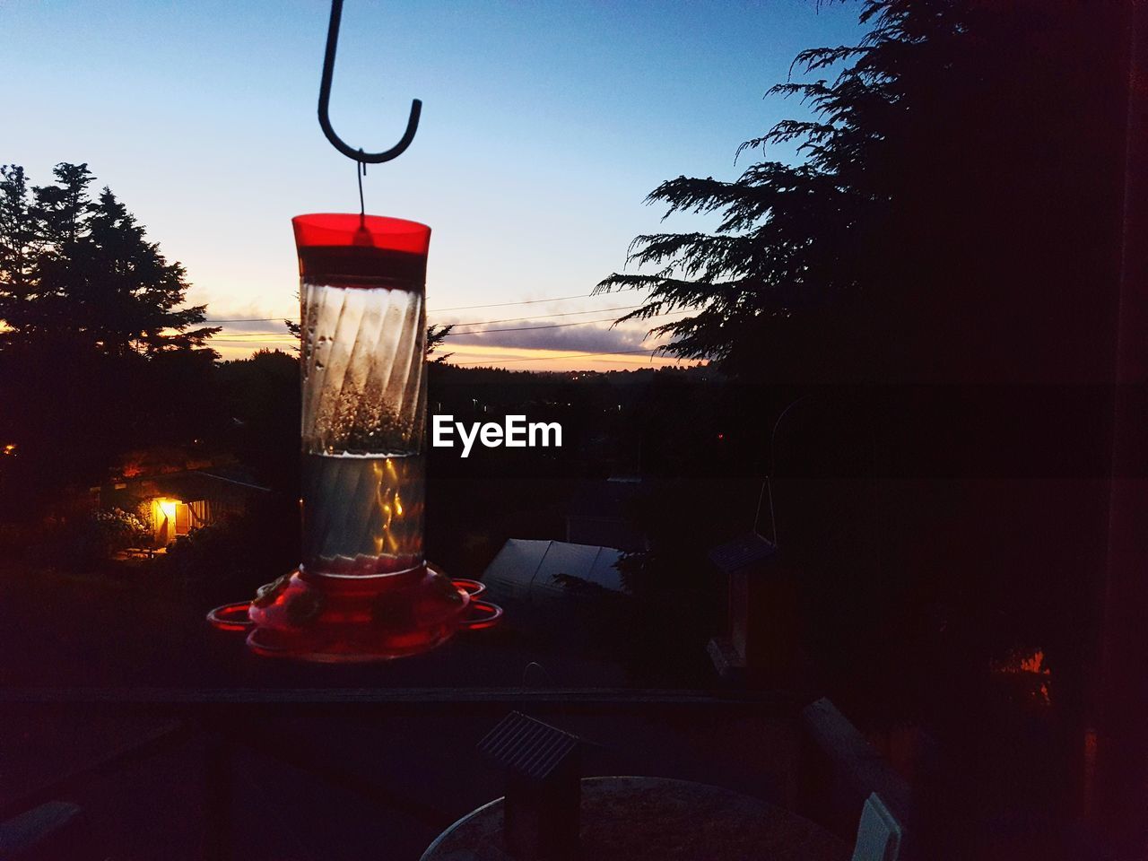 CLOSE-UP OF WINE GLASS ON TABLE AGAINST ILLUMINATED LIGHT