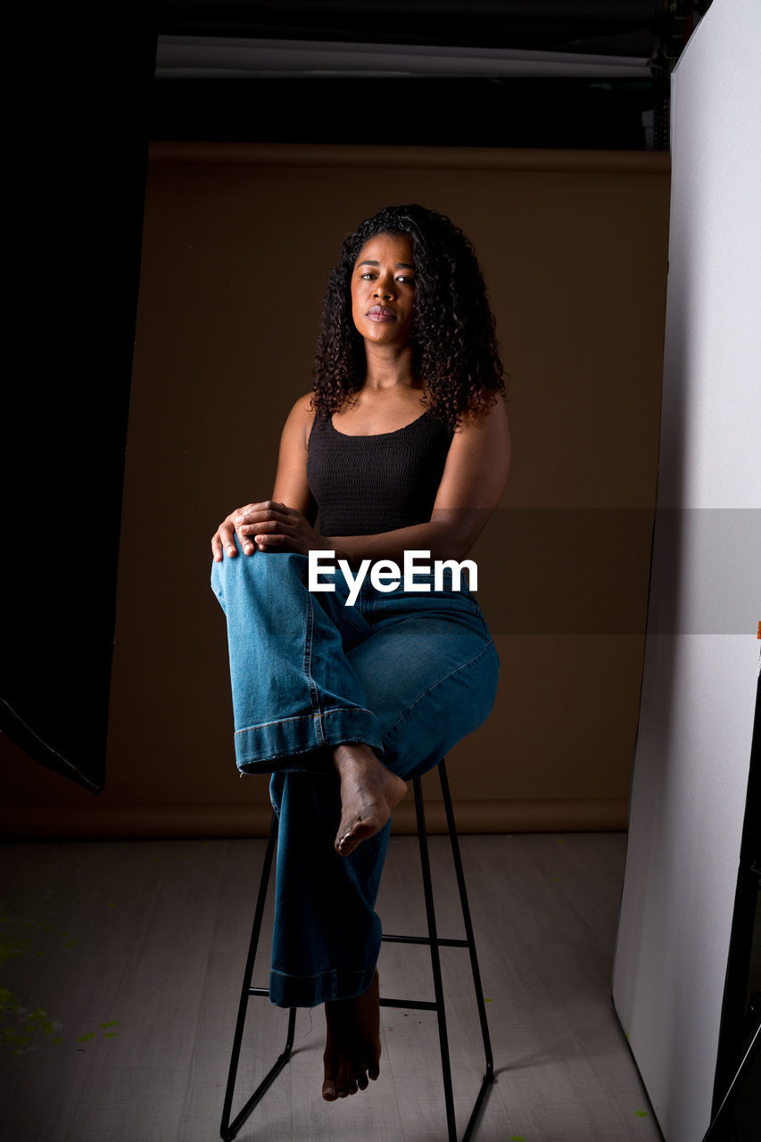 portrait of young woman standing against wall at home