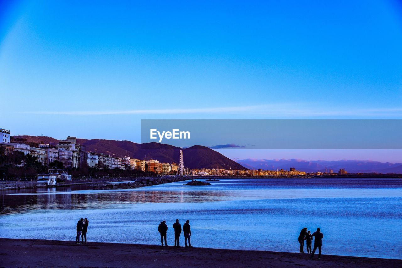 PEOPLE ON BEACH AGAINST BLUE SKY