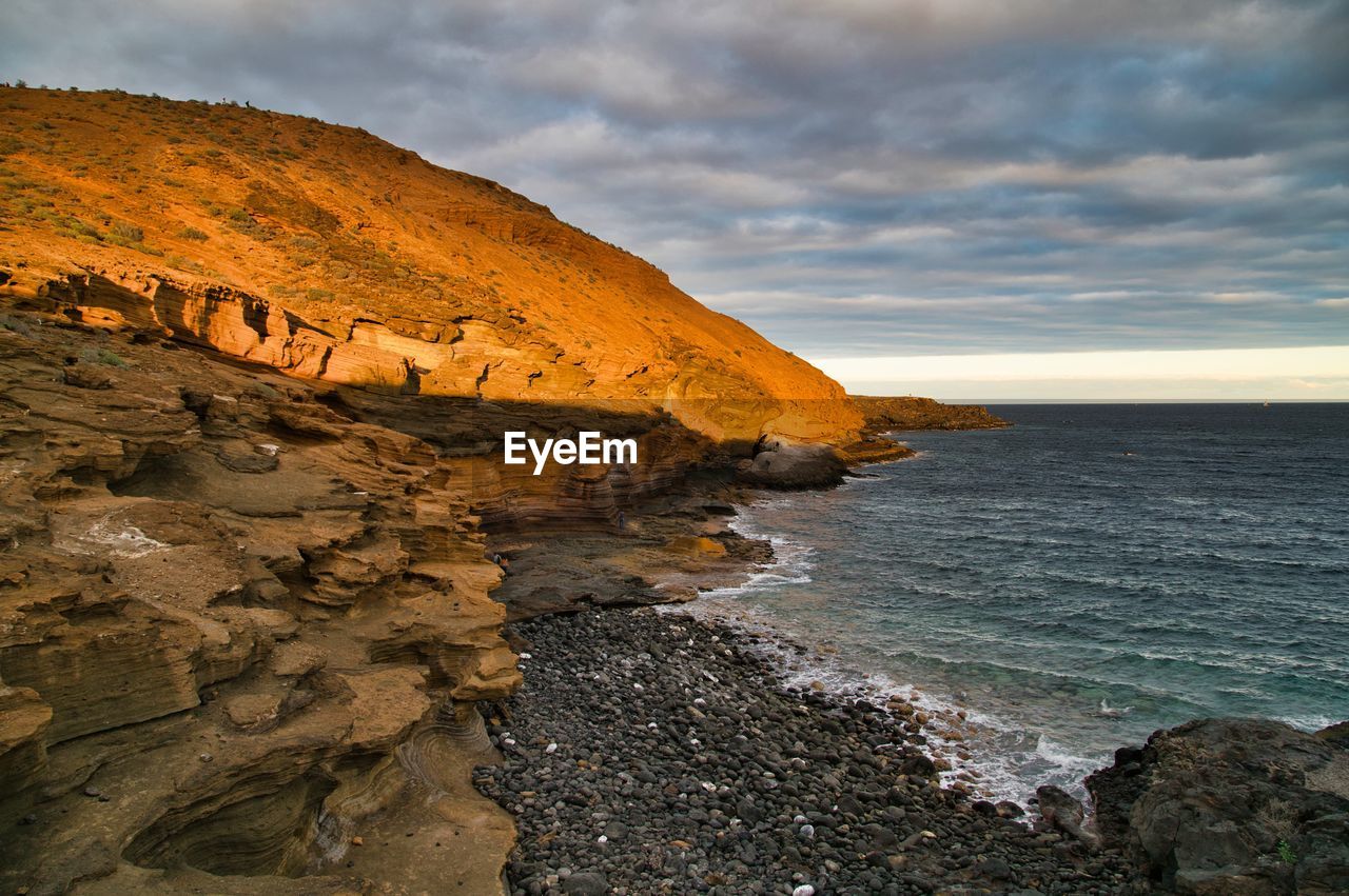 Rock formations by sea against sky