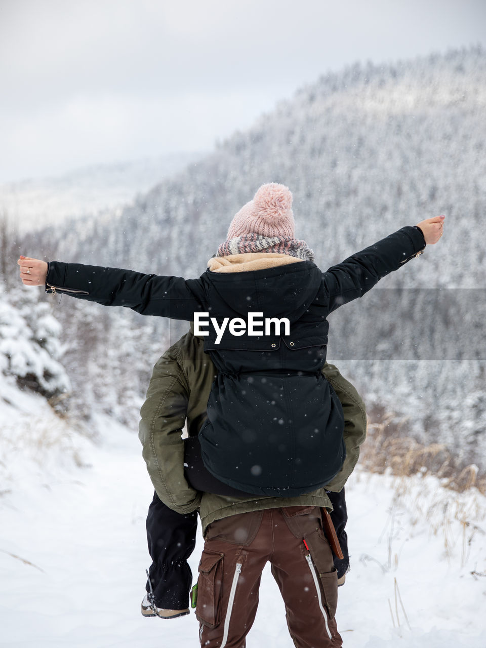 REAR VIEW OF MAN STANDING IN SNOW