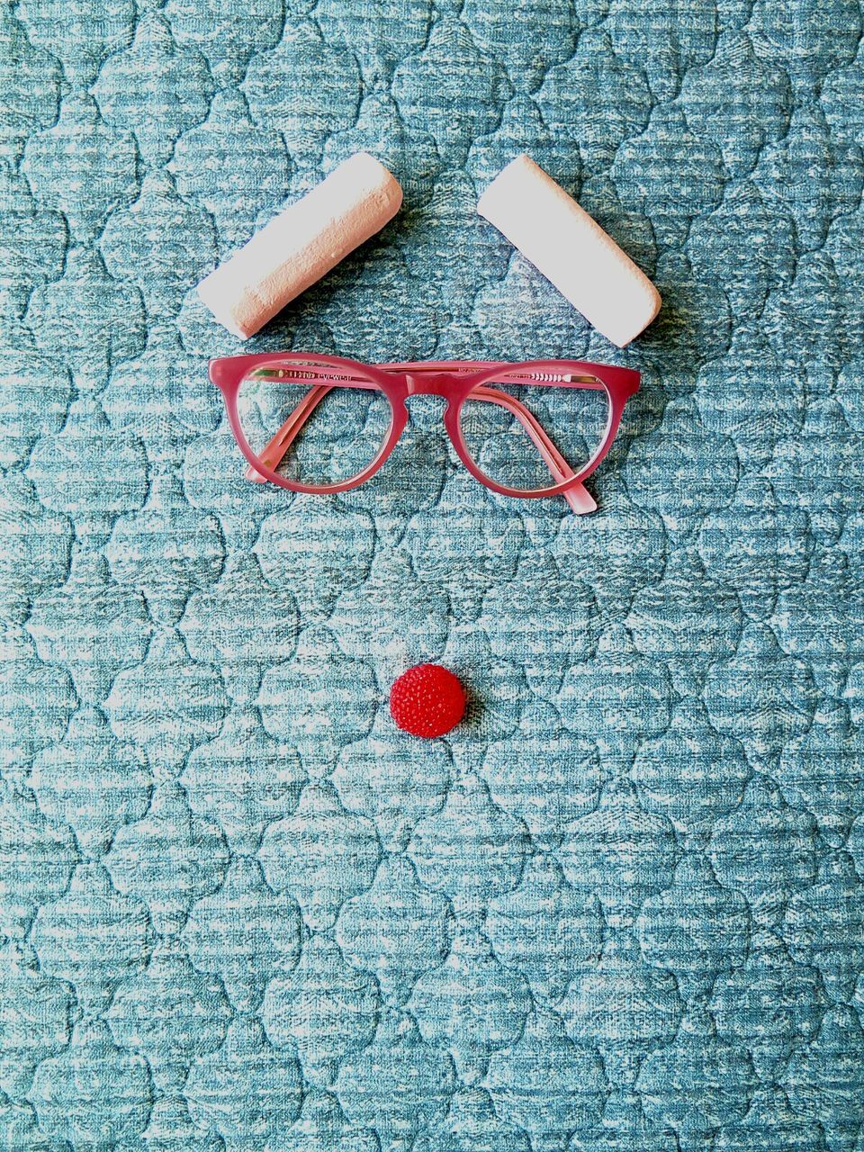 Directly above view of pink eyeglasses and candies making anthropomorphic face