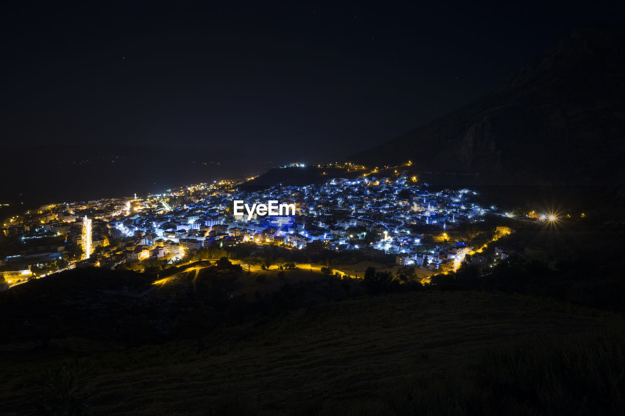 HIGH ANGLE VIEW OF ILLUMINATED BUILDINGS AT NIGHT