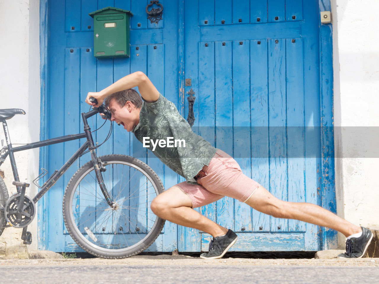 Young man pushing bicycle by doorway