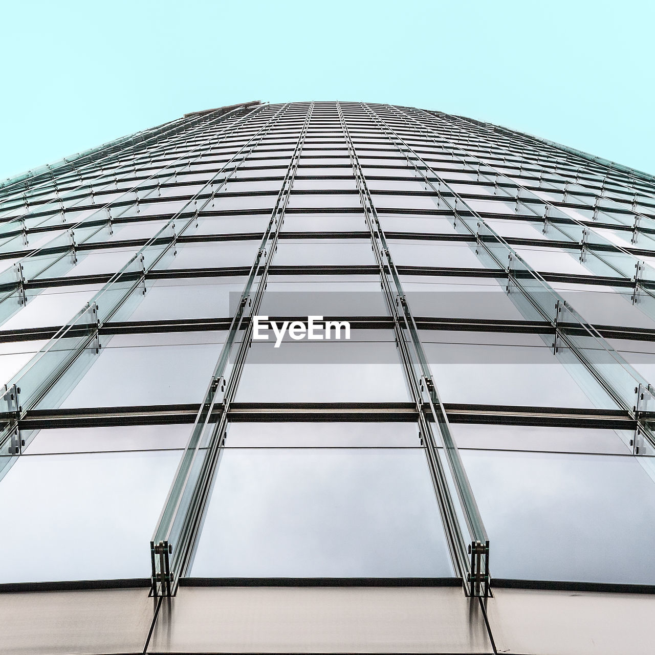 LOW ANGLE VIEW OF MODERN GLASS BUILDING AGAINST SKY