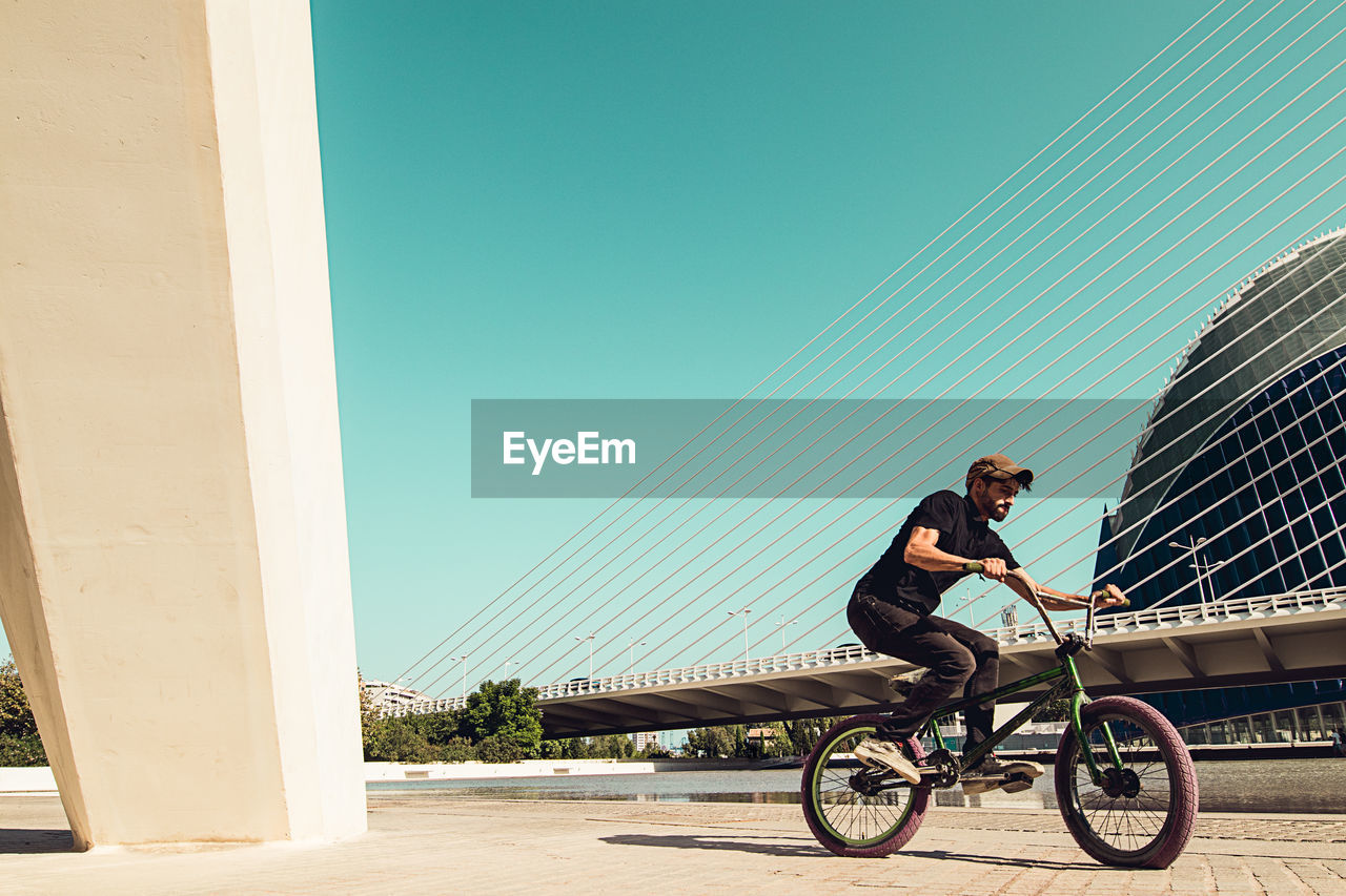 Man riding bmx cycle on footpath in city