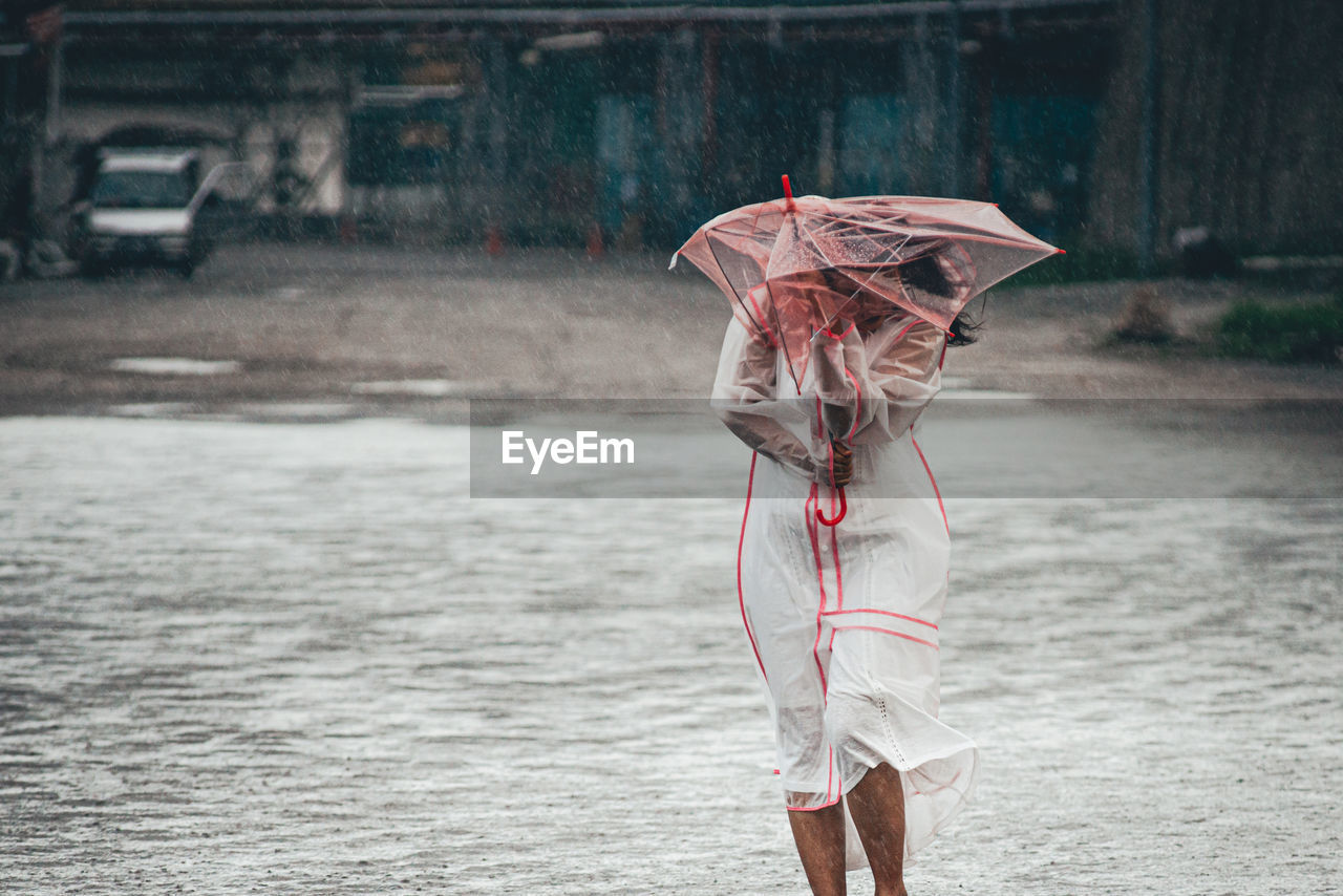Young woman holding umbrella during rainy season