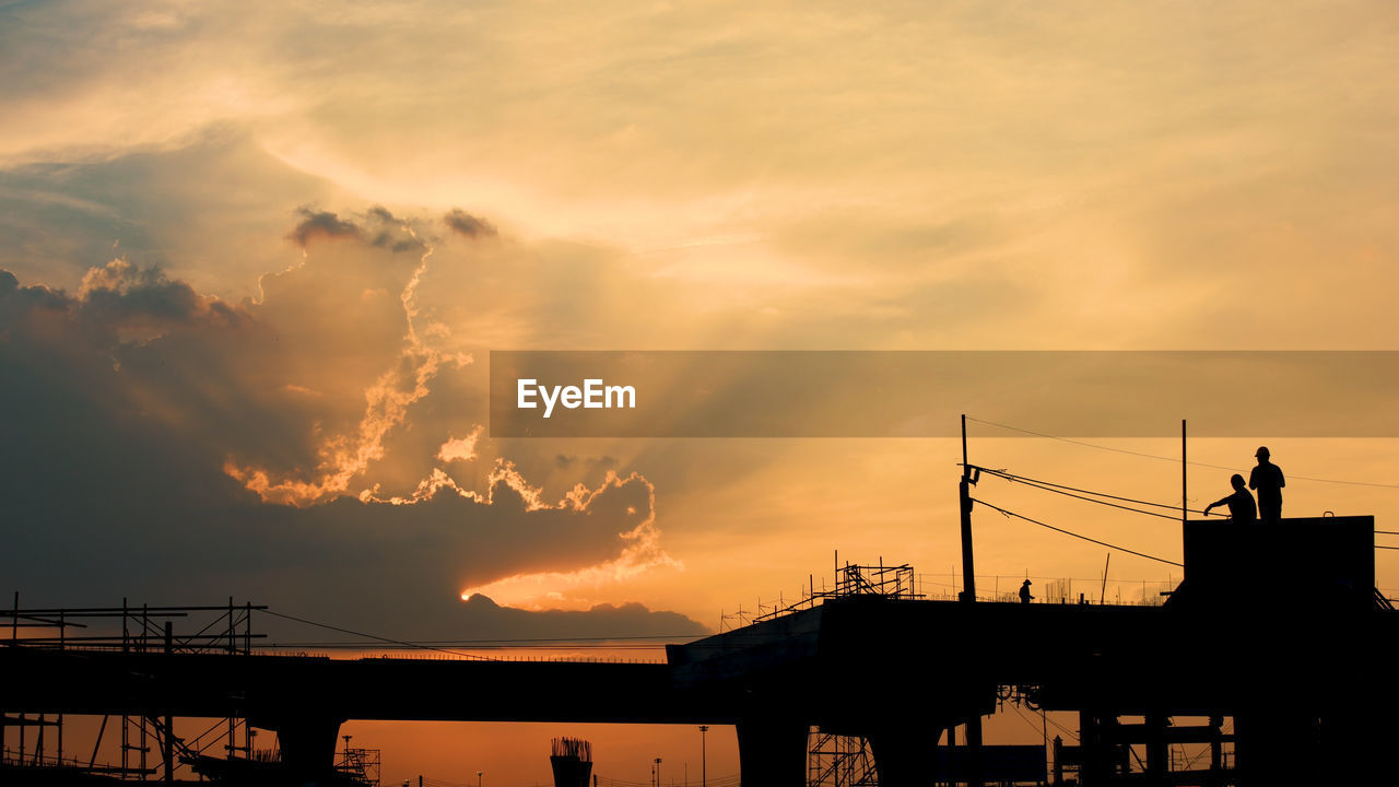 LOW ANGLE VIEW OF SILHOUETTE BUILDING AGAINST DRAMATIC SKY