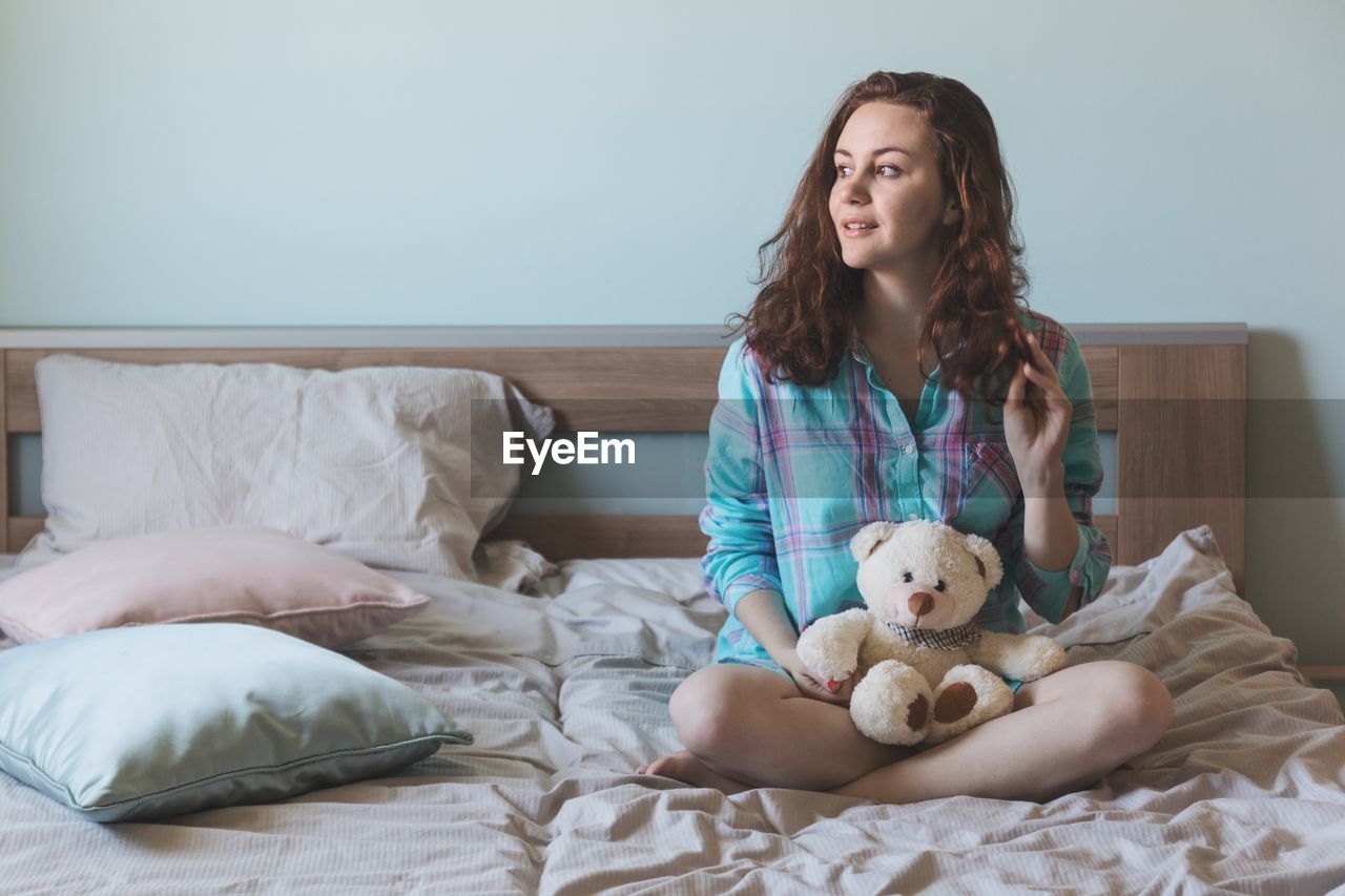 Portrait of young woman sitting on bed