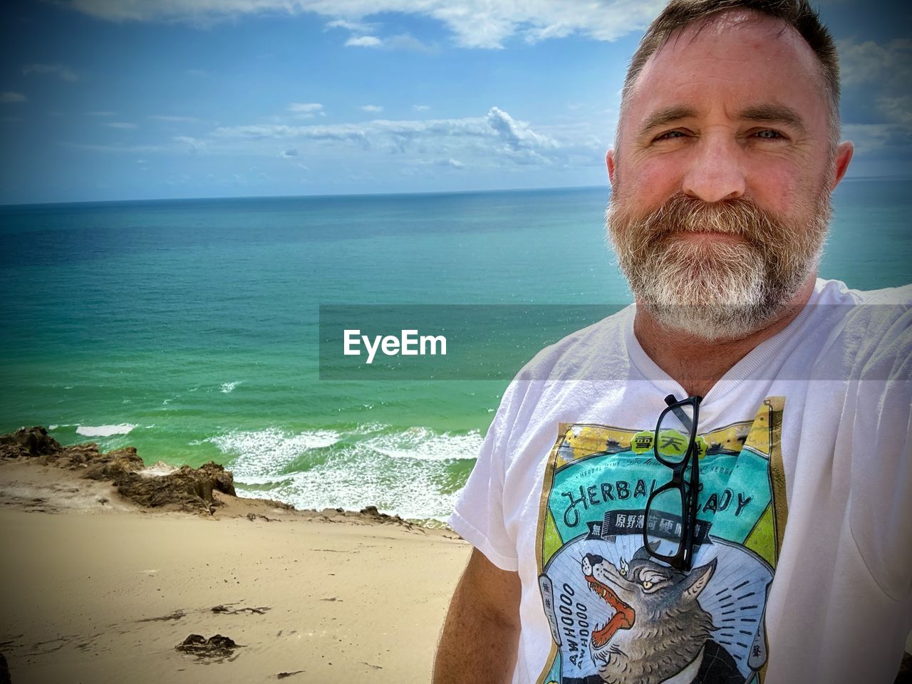 sea, water, beach, one person, land, portrait, adult, sky, vacation, men, beard, facial hair, nature, looking at camera, mature adult, horizon over water, ocean, front view, horizon, smiling, holiday, leisure activity, person, trip, cloud, blue, day, beauty in nature, casual clothing, scenics - nature, lifestyles, emotion, happiness, clothing, sand, outdoors, human face, travel, standing, travel destinations, relaxation, coast, waist up, sunlight, headshot