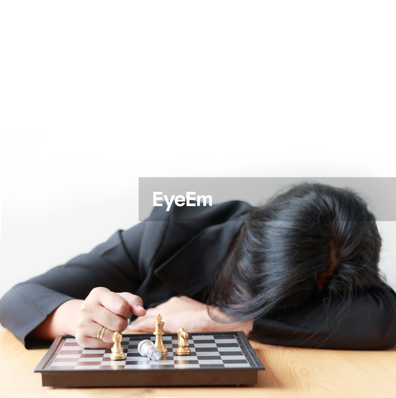 Woman sleeping by chess board at table