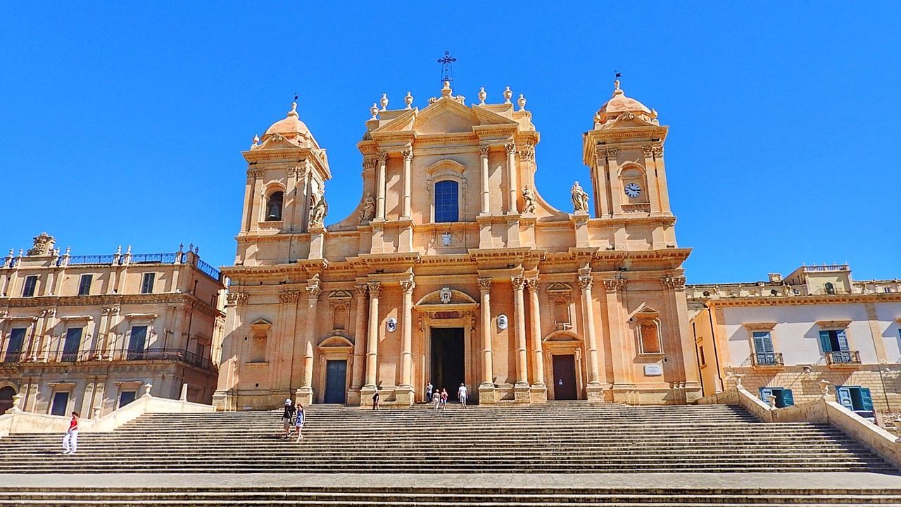 Low angle view of people at noto cathedral against clear sky