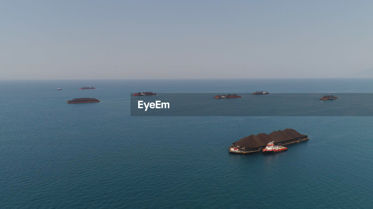 Aerial view barges full coal anchored at sea near coal fired power station waiting be transported. 