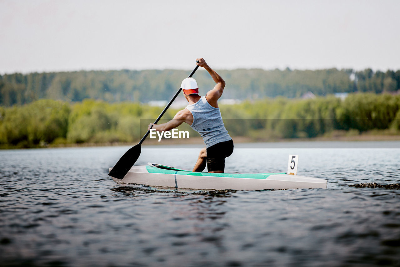 Rear view of man canoeing on lake