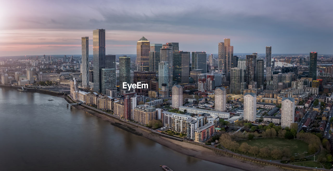 AERIAL VIEW OF RIVER AMIDST BUILDINGS AGAINST SKY IN CITY