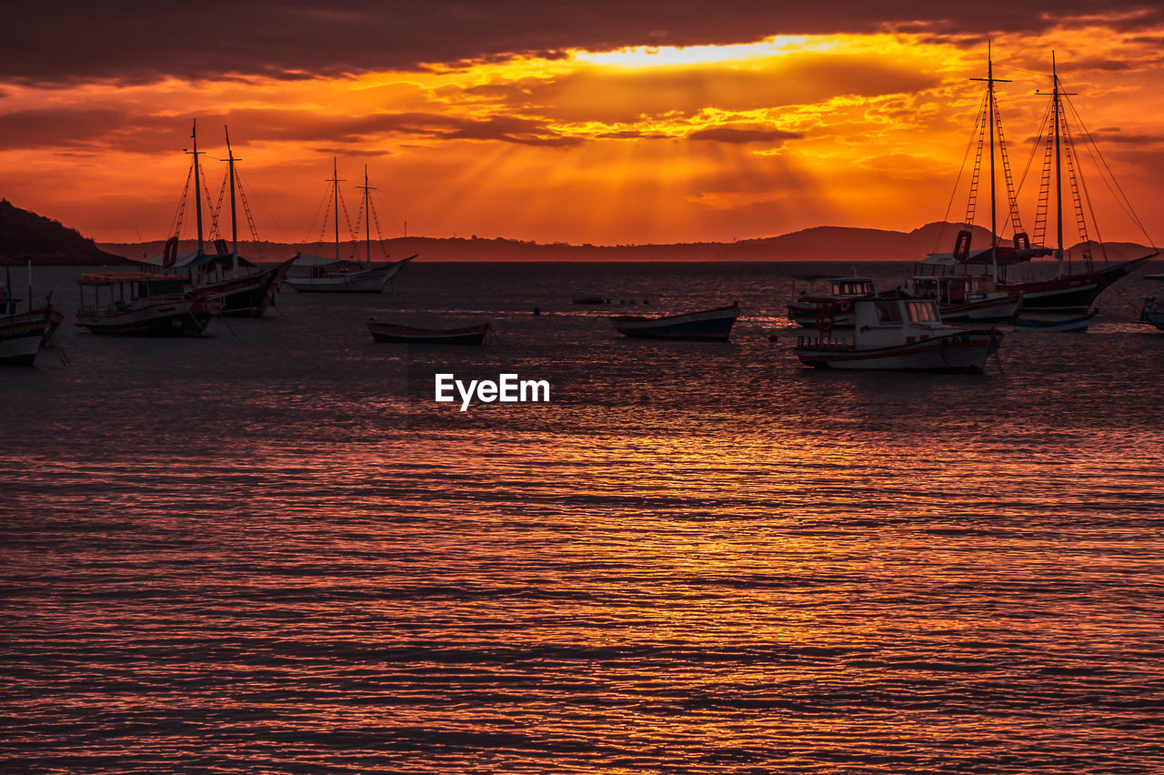 SAILBOATS MOORED AT HARBOR AGAINST DRAMATIC SKY