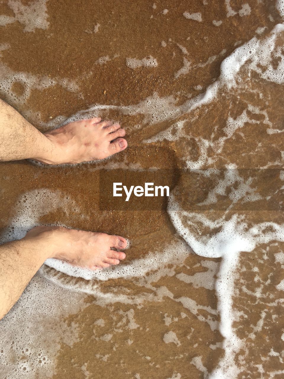 LOW SECTION OF PERSON RELAXING ON BEACH