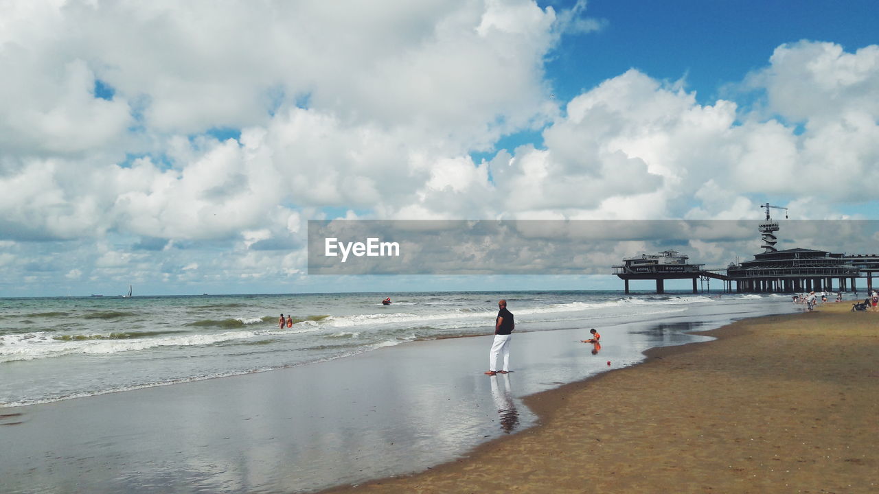 People at beach against cloudy sky