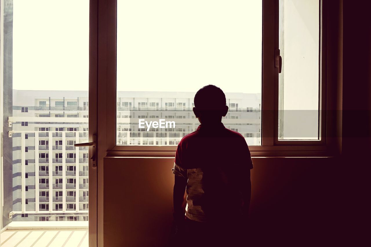 Rear view of woman looking through window