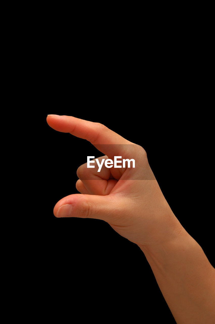 Cropped image of hand gesturing over black background