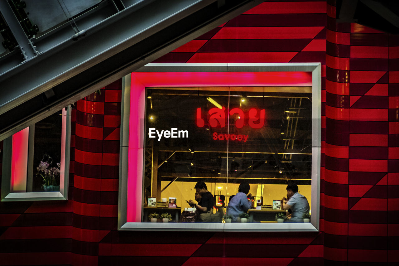 PEOPLE IN ILLUMINATED RED BUILDING