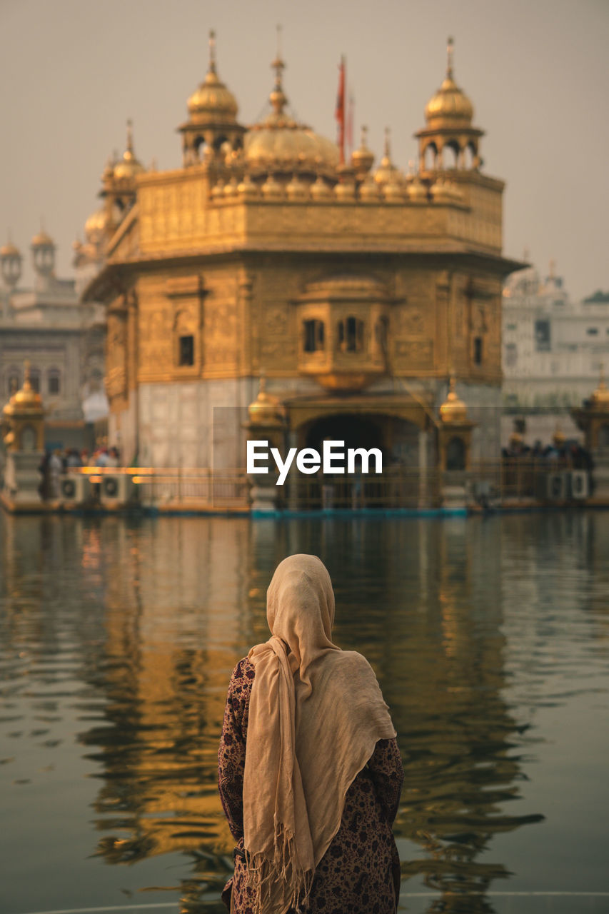 Rear view of woman on the river against the golden temple