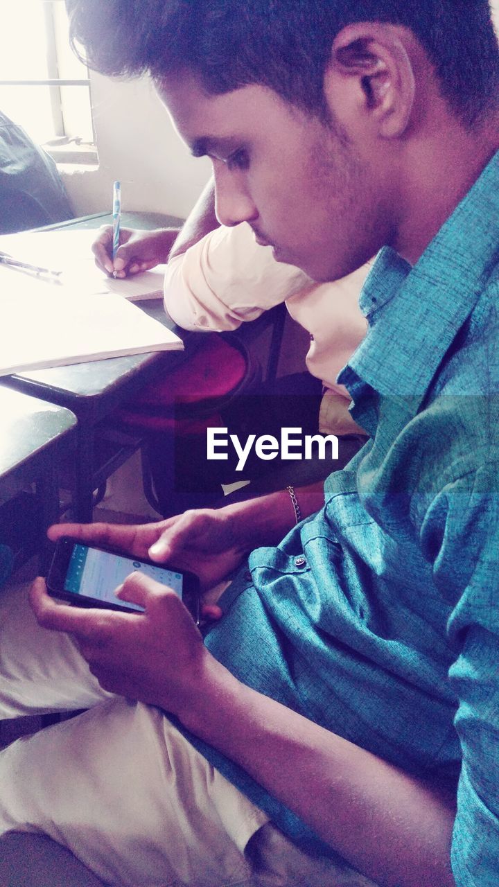 SIDE VIEW OF A YOUNG MAN USING LAPTOP