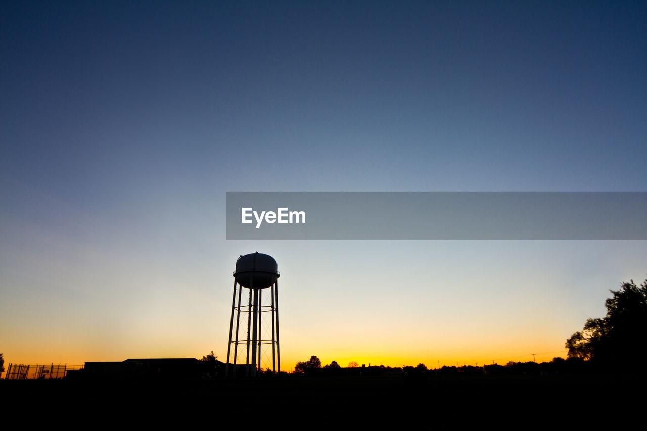 Silhouette water tower against clear sky during sunset