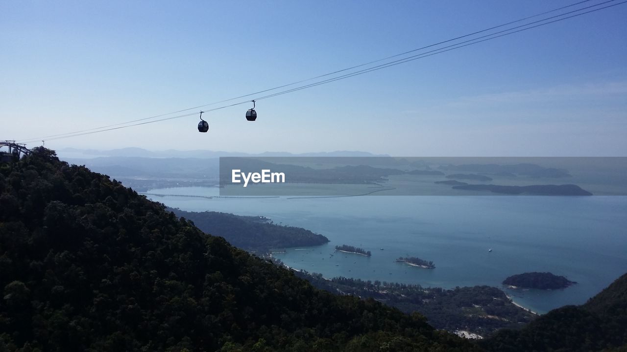 OVERHEAD CABLE CARS OVER MOUNTAINS AGAINST CLEAR SKY