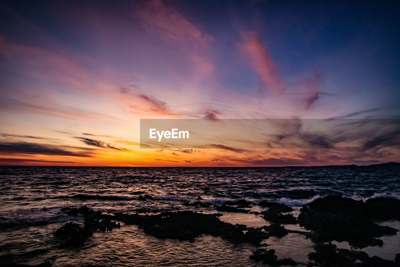 SCENIC VIEW OF BEACH AGAINST SKY DURING SUNSET