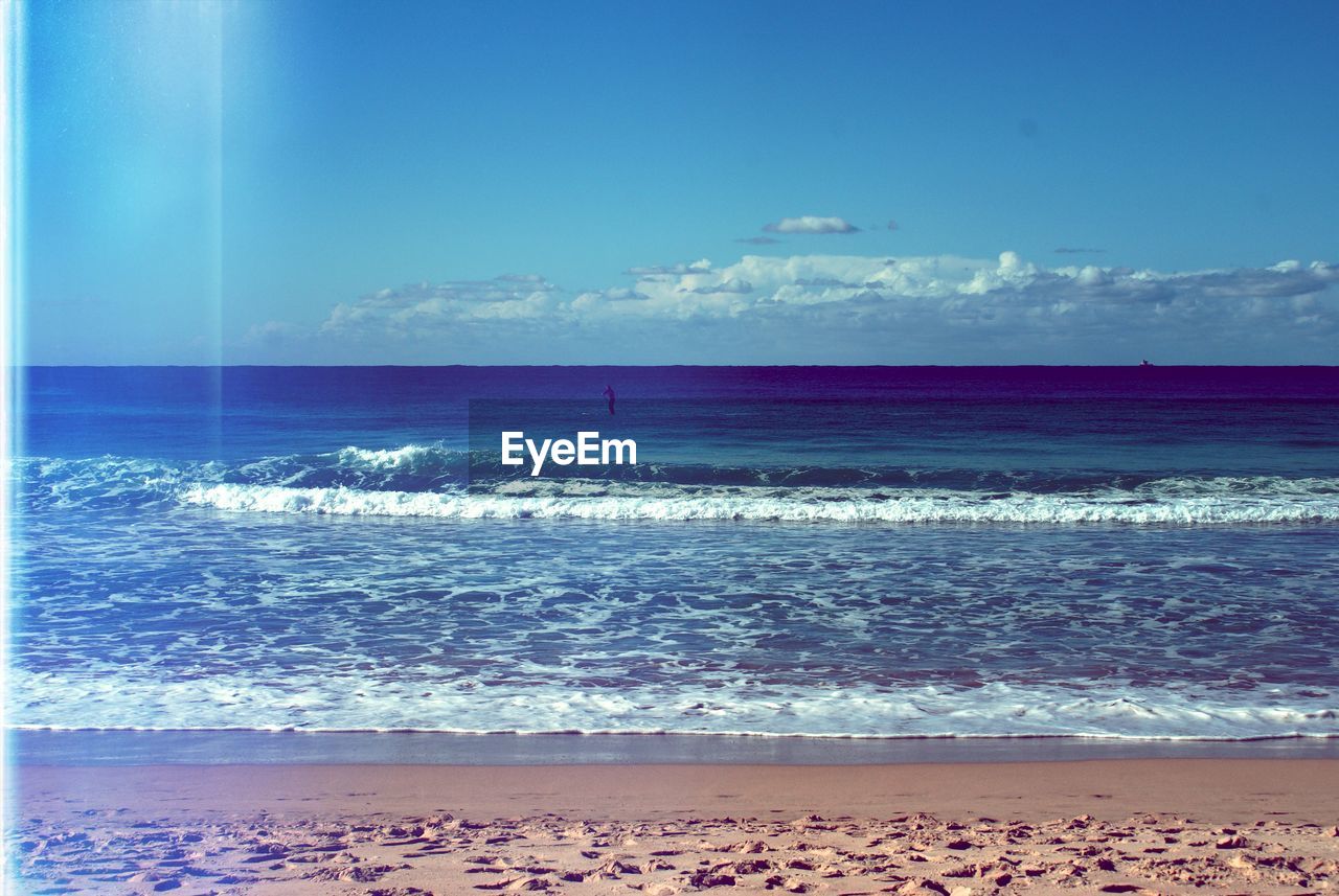 View of calm beach against blue sky