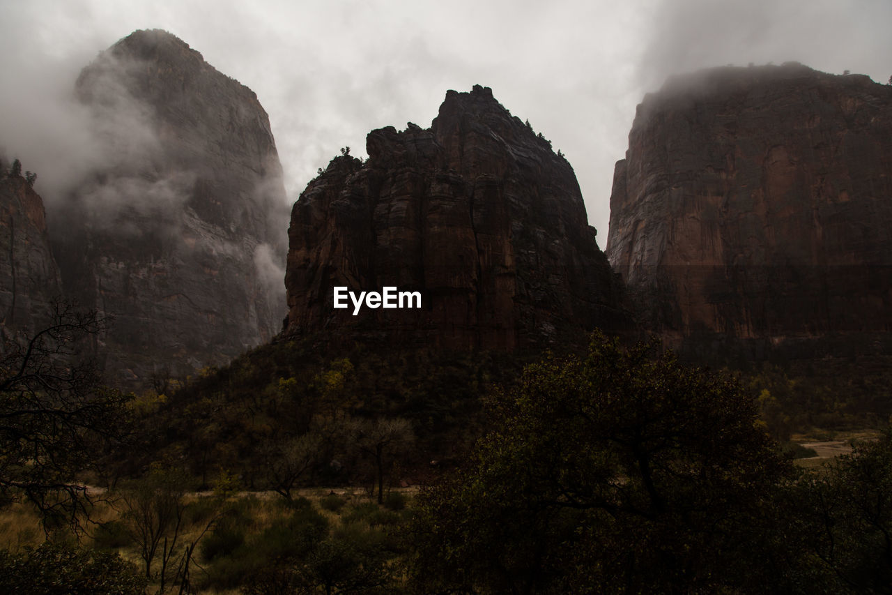 Low angle view of majestic mountains against cloudy sky