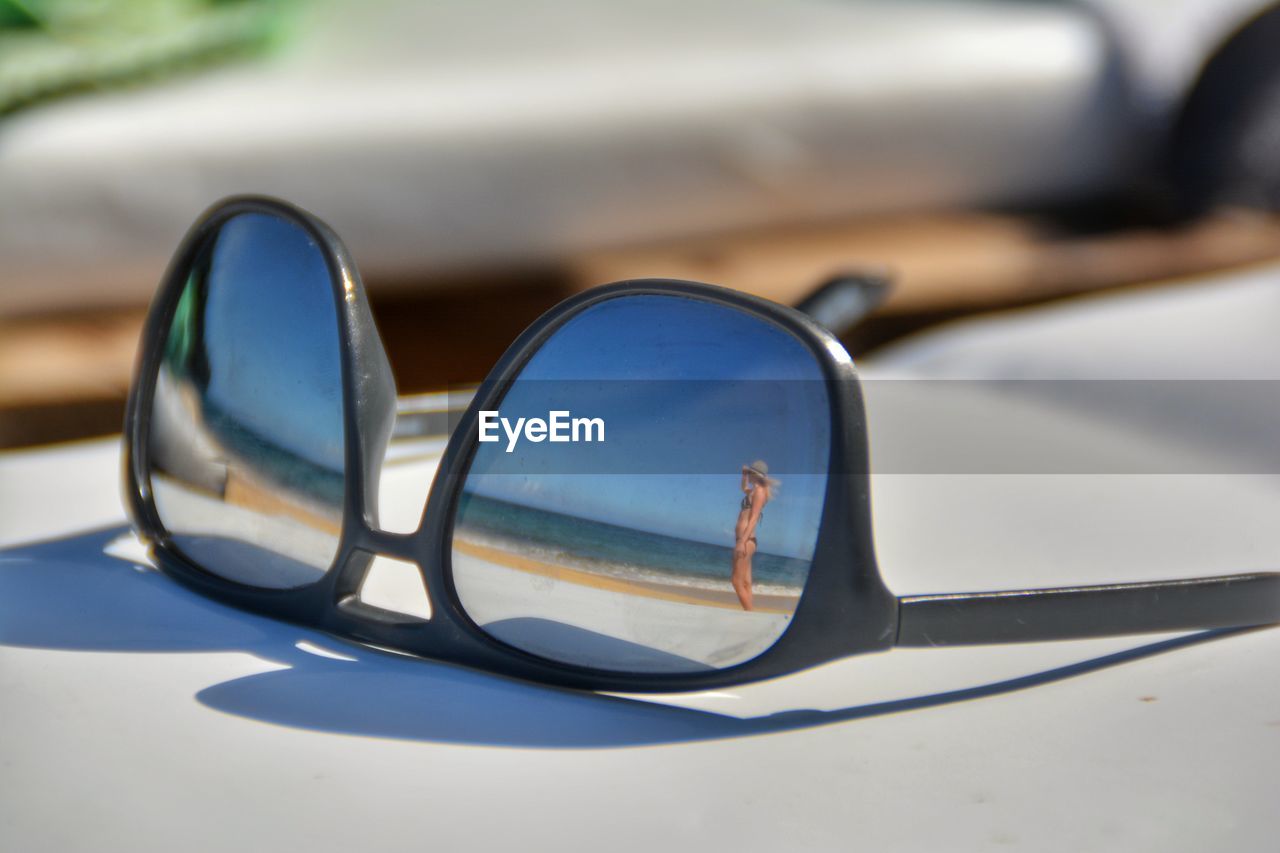 Woman in bikini at beach reflecting on sunglasses