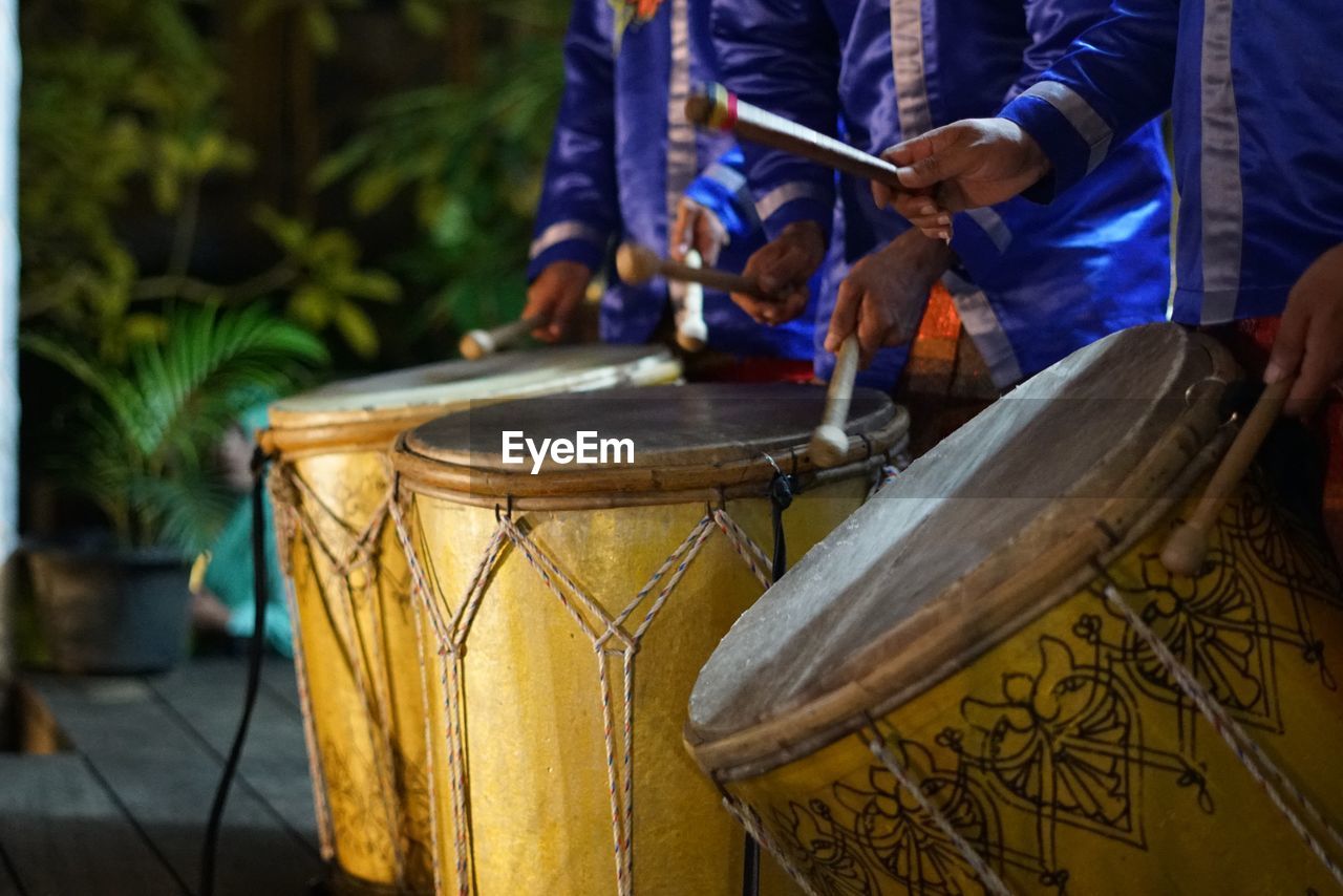 Midsection of men playing drum during event at night