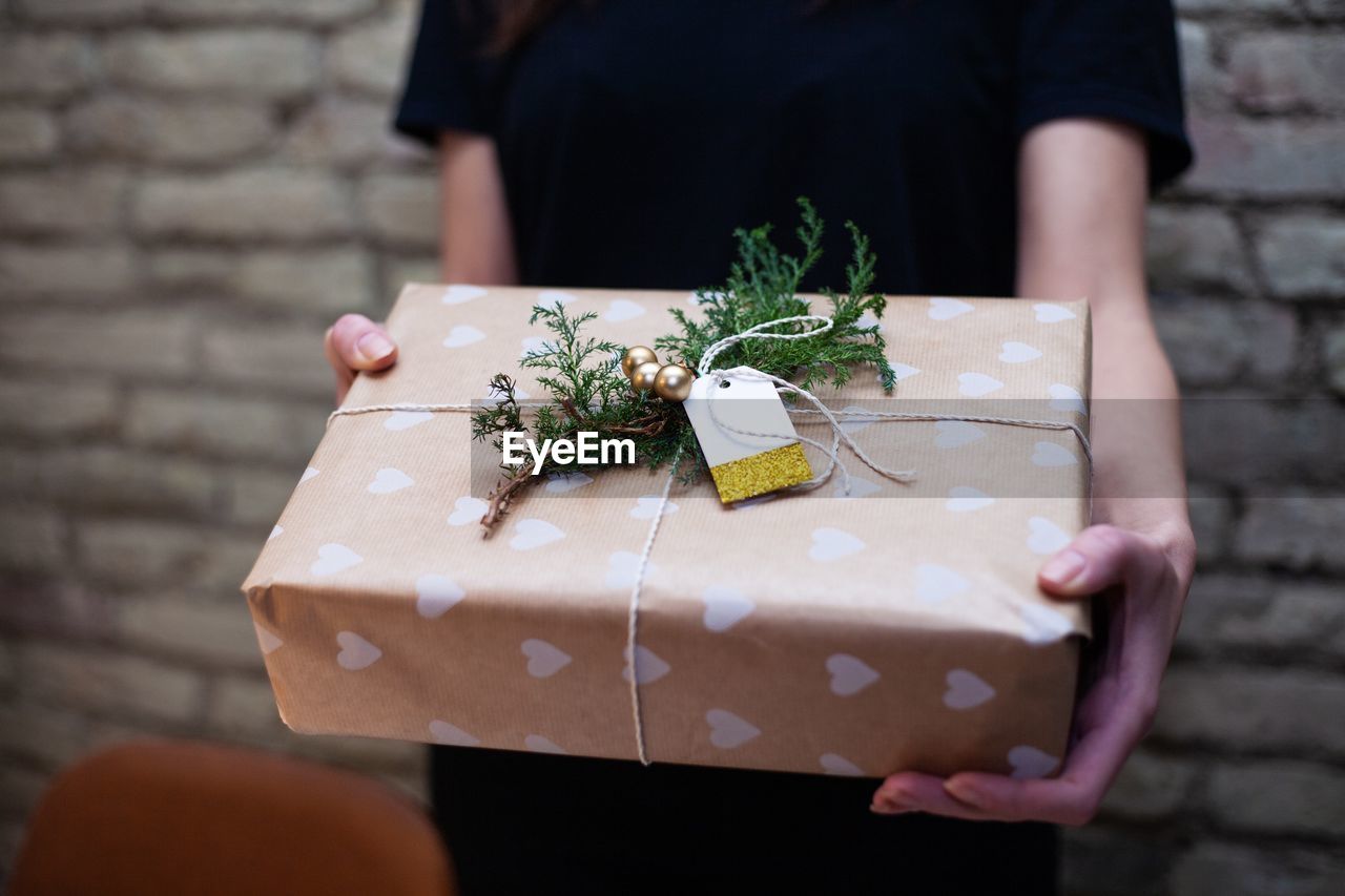 Midsection of woman holding wrapped christmas present at home