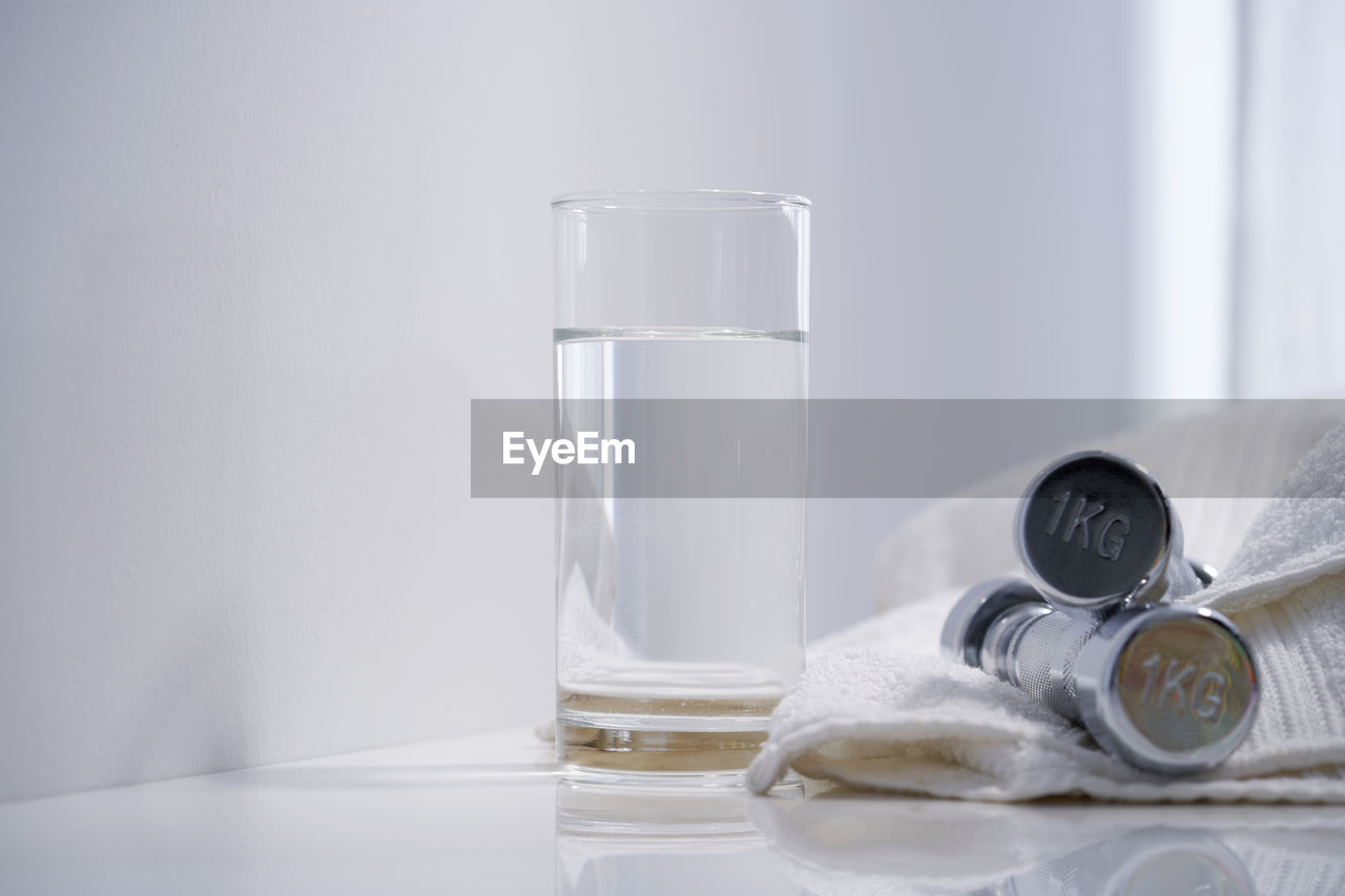 Healthy liftstyle concept- water with dumbbell and towel on white background