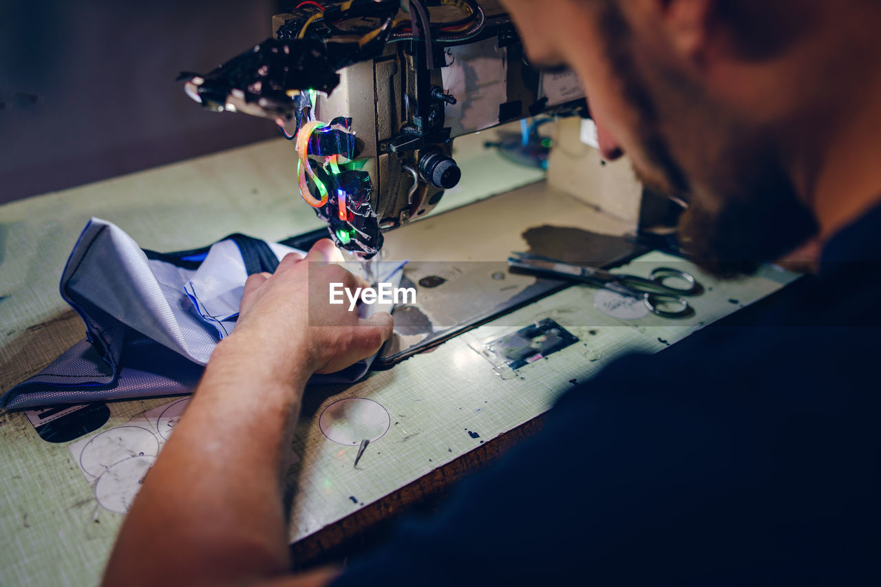 Midsection of man working on sewing machine