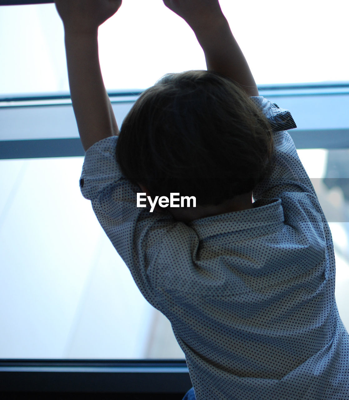 Rear view of child standing by window