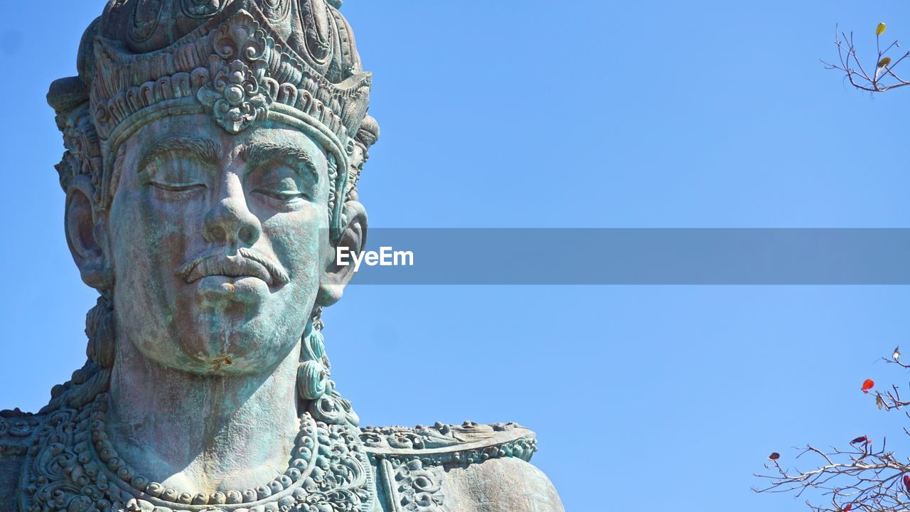 Low angle view of male statue against clear blue sky