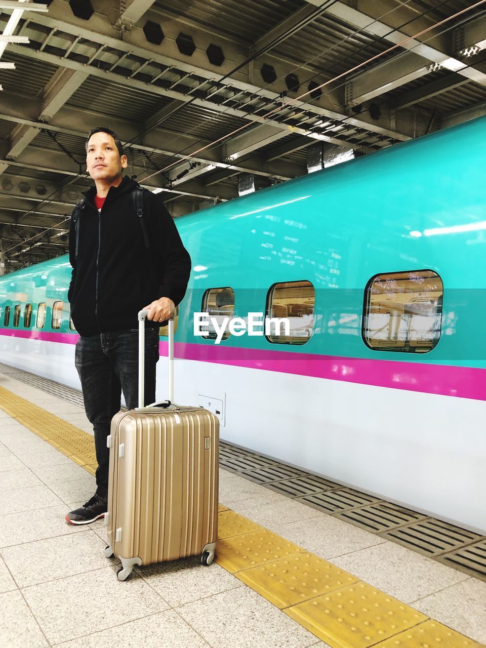 Full length of man with luggage standing at railroad station platform