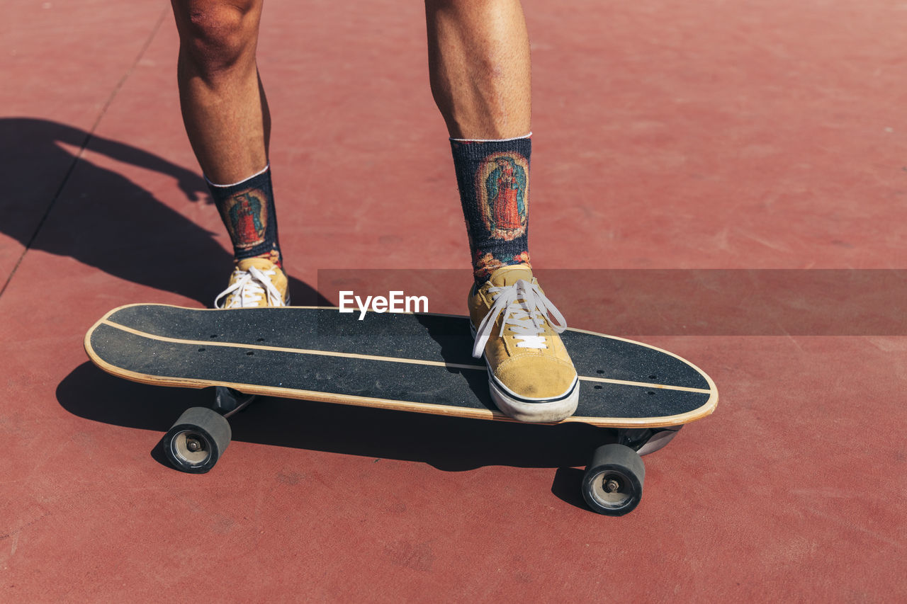 Young man skateboarding at basketball court on sunny day