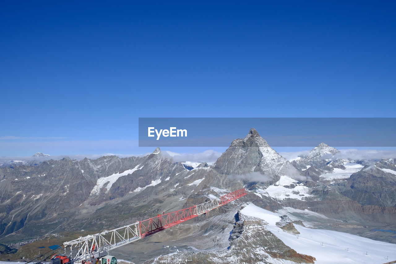 Scenic view of snowcapped mountains against clear blue sky