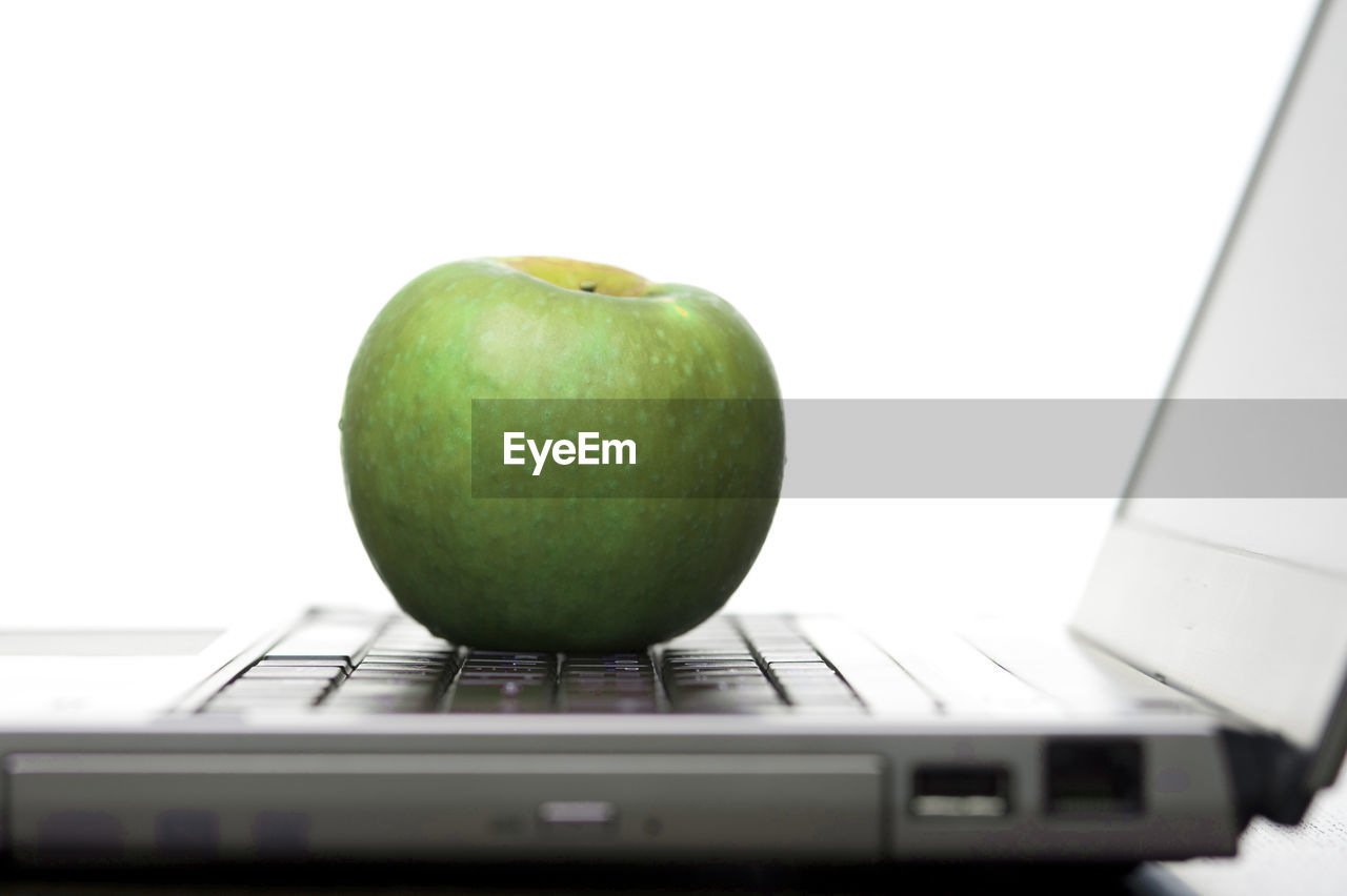 Granny smith apple on laptop against white background