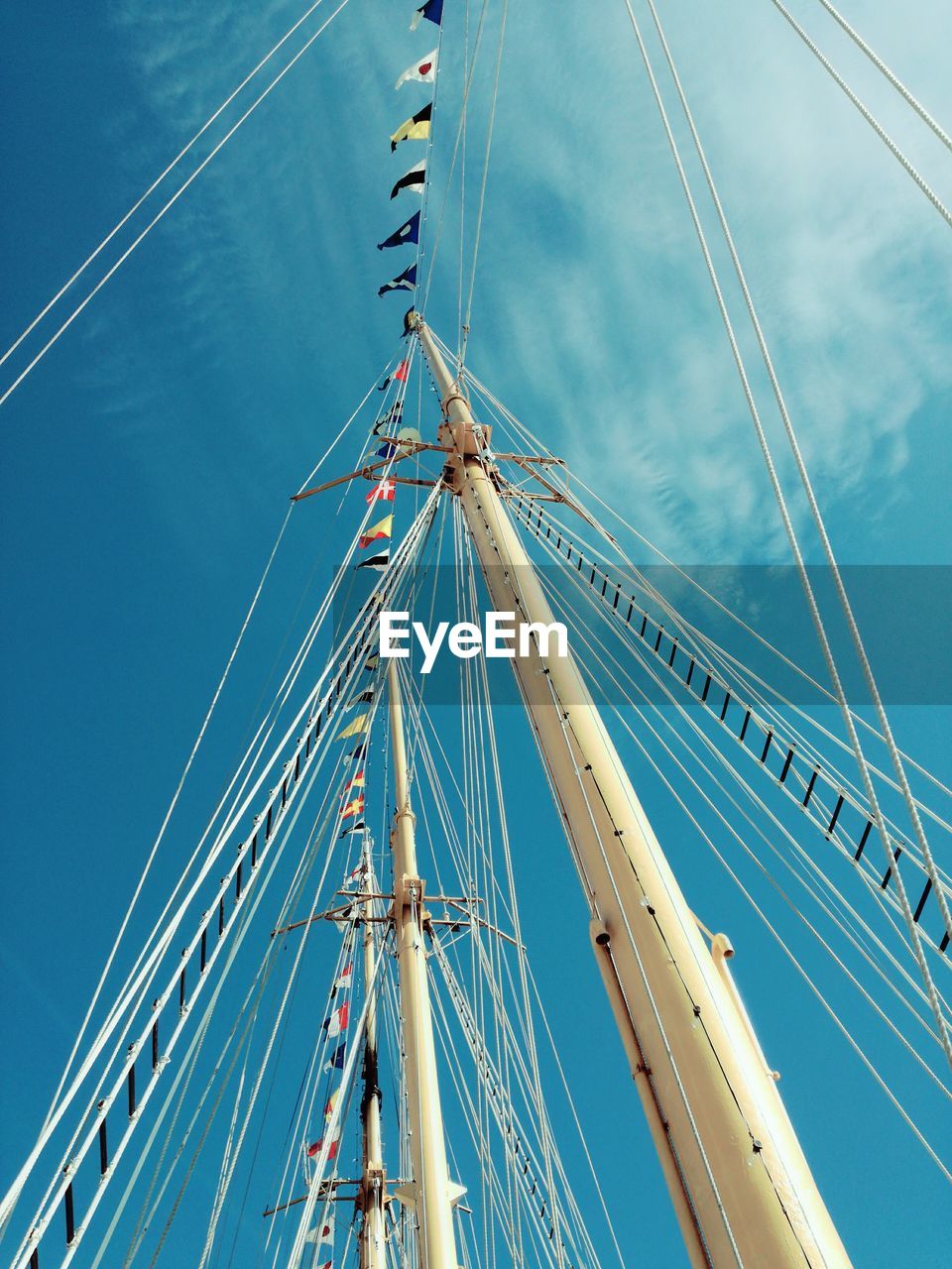 Low angle view of masts against blue sky