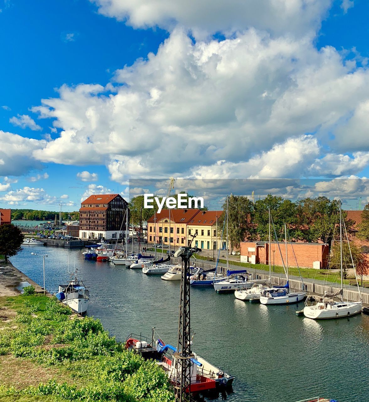 Sailboats moored on river by buildings in city against sky